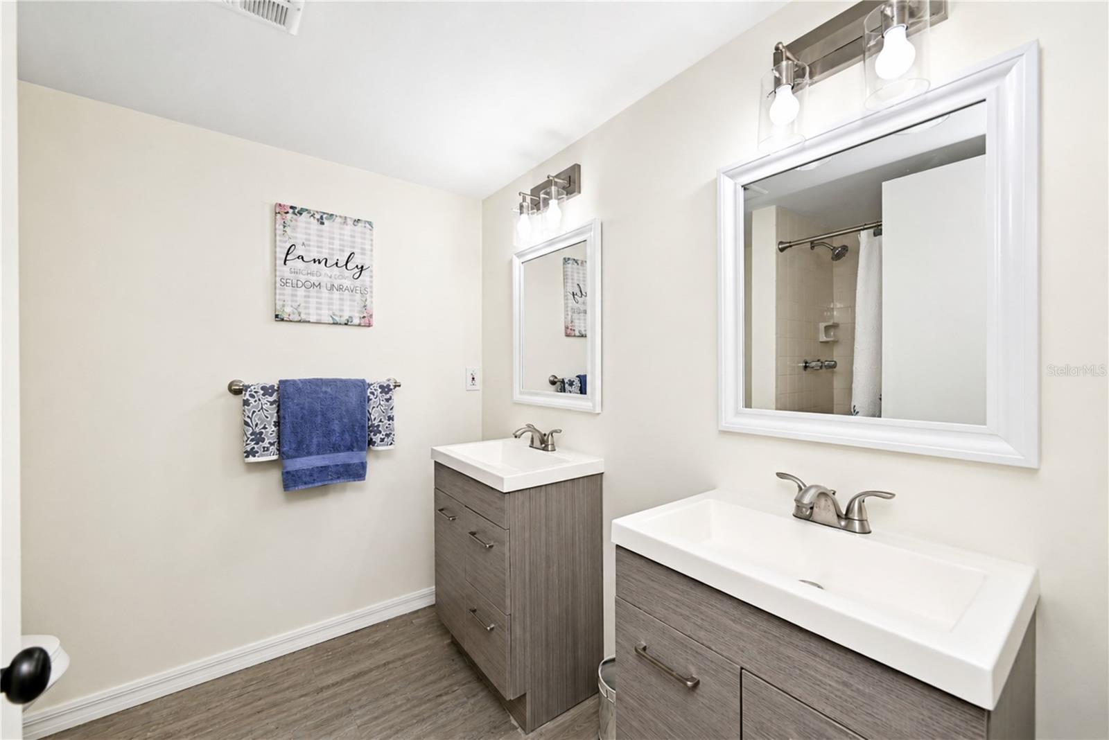 Primary bedroom's updated ensuite bathroom boasts dual vanities and a walk-in shower