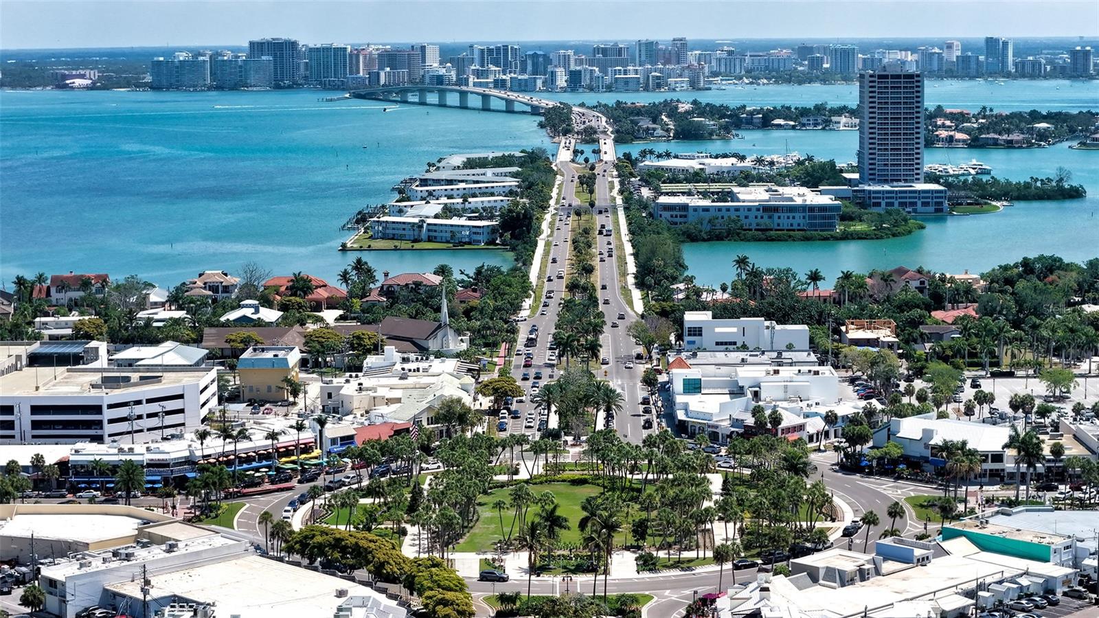 A stunning aerial perspective from St. Armands Circle toward downtown Sarasota, showcasing the iconic skyline framed by sparkling Bay waters.