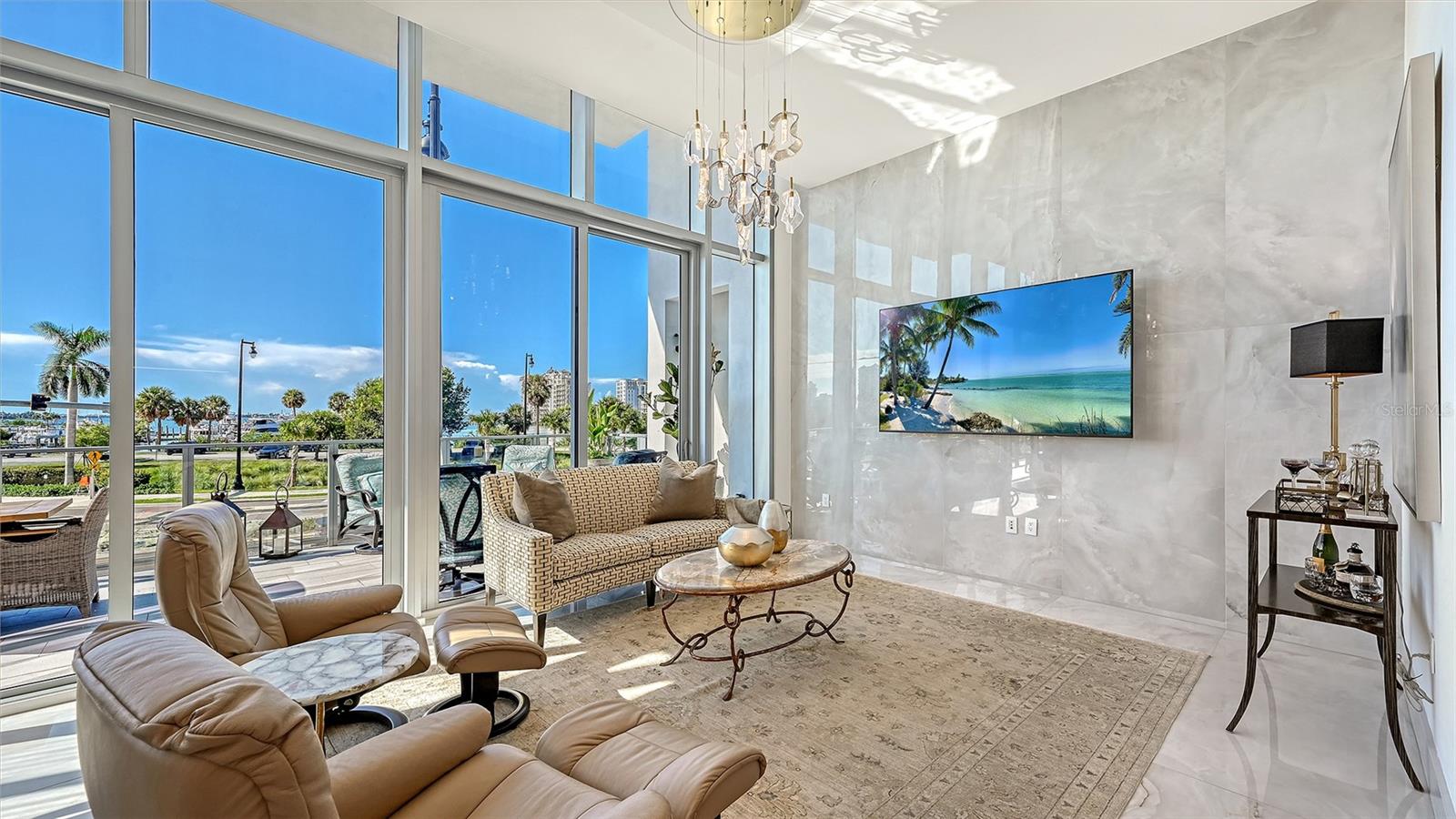 The grand great room showcases over 28 feet of soaring 12-foot floor-to-ceiling windows, capturing breathtaking panoramic views of Sarasota Bay.