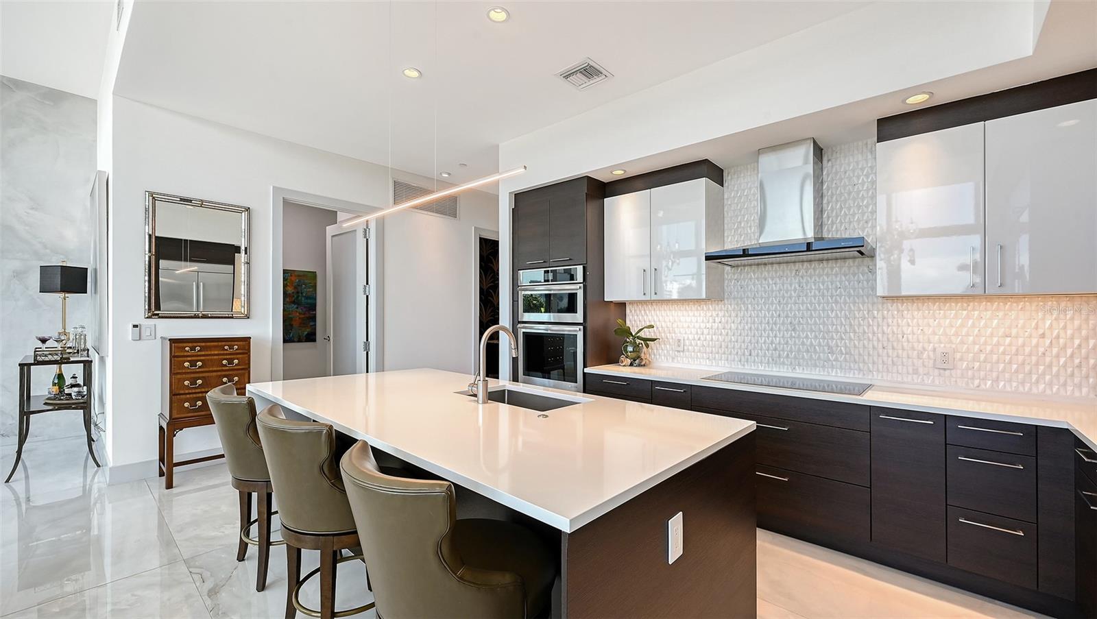 Open-concept kitchen featuring rich dark cabinetry, sleek countertops, and a spacious island with bar seating