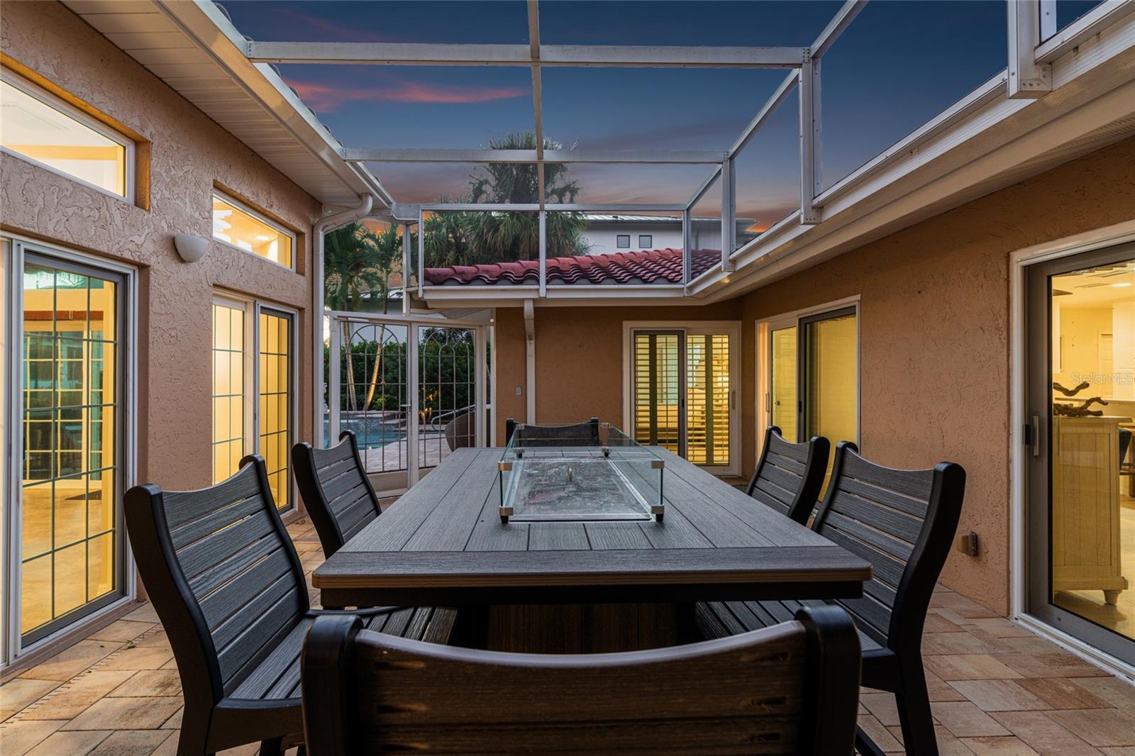 Twilight brings a warm glow to the fully screened central courtyard lanai, complete with a tabletop fire pit.