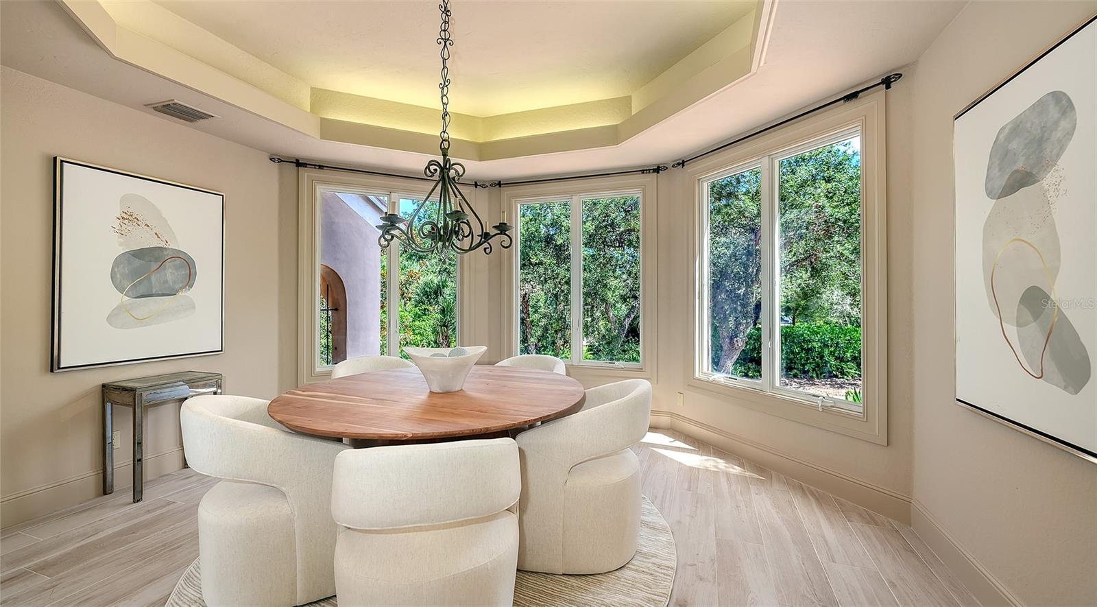A beautifully defined dining room offers an intimate setting enhanced by a tray ceiling, chandelier and abundant natural light.