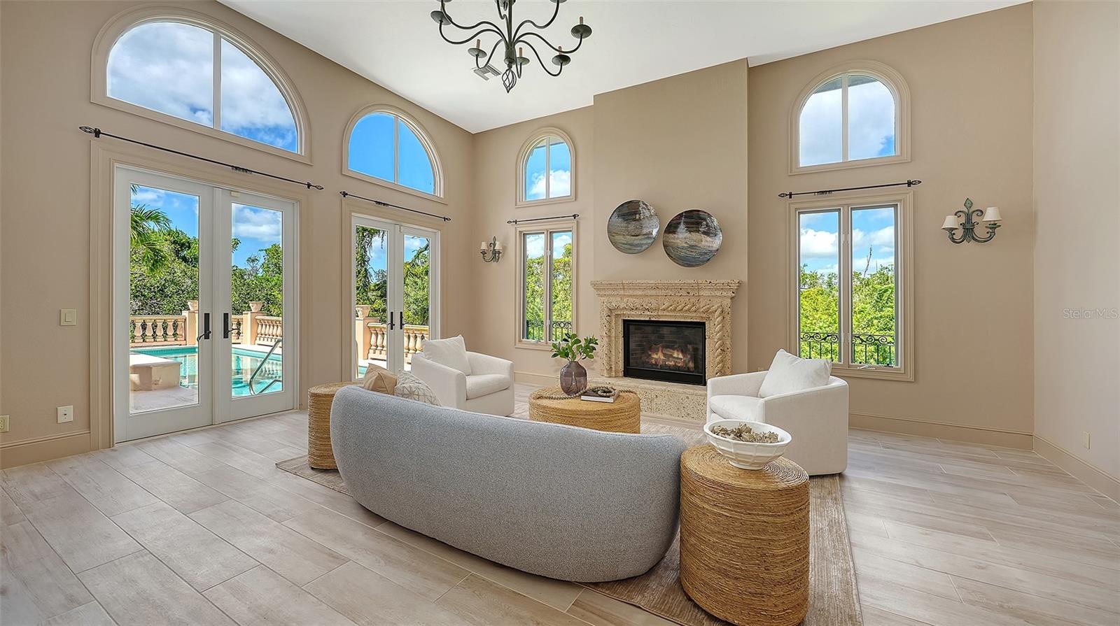 Walls of windows and French doors fill the great room with natural light while connecting the interior to the surrounding landscape.