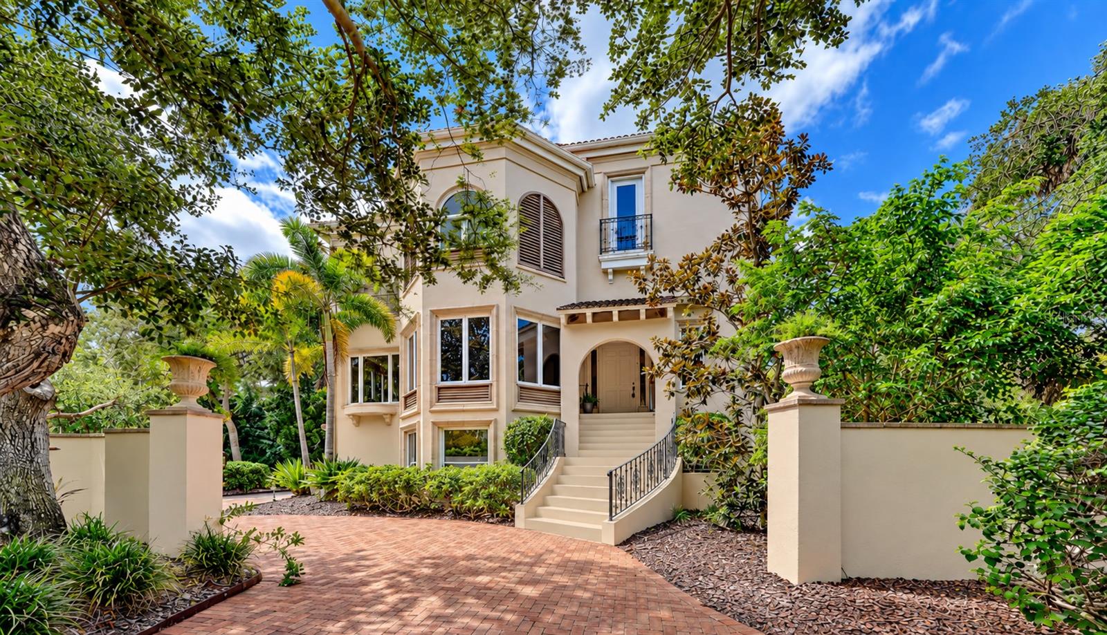Mizner inspired architecture and lush tropical landscaping create an impressive introduction to this private bayfront residence. Mizner inspired architecture and lush tropical landscaping create an impressive introduction to this private bayfront residence.