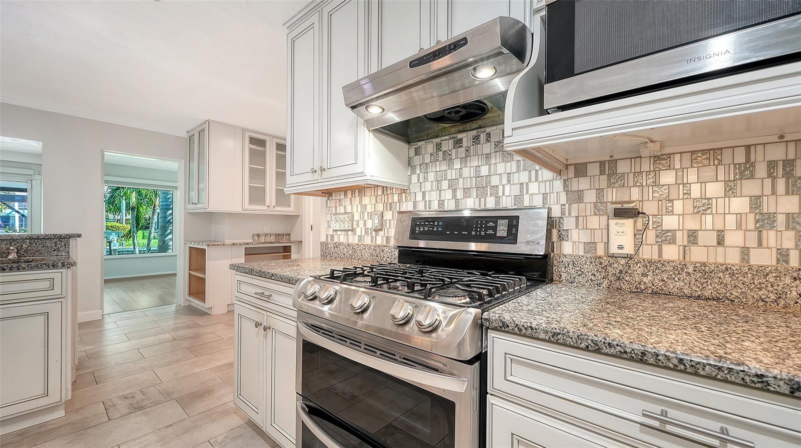 A gas range and detailed tile backsplash anchor the kitchen.