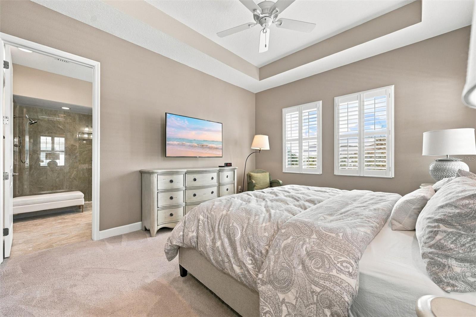 spacious primary suite, featuring an elegant tray ceiling and two walk-in closets for ample storage.