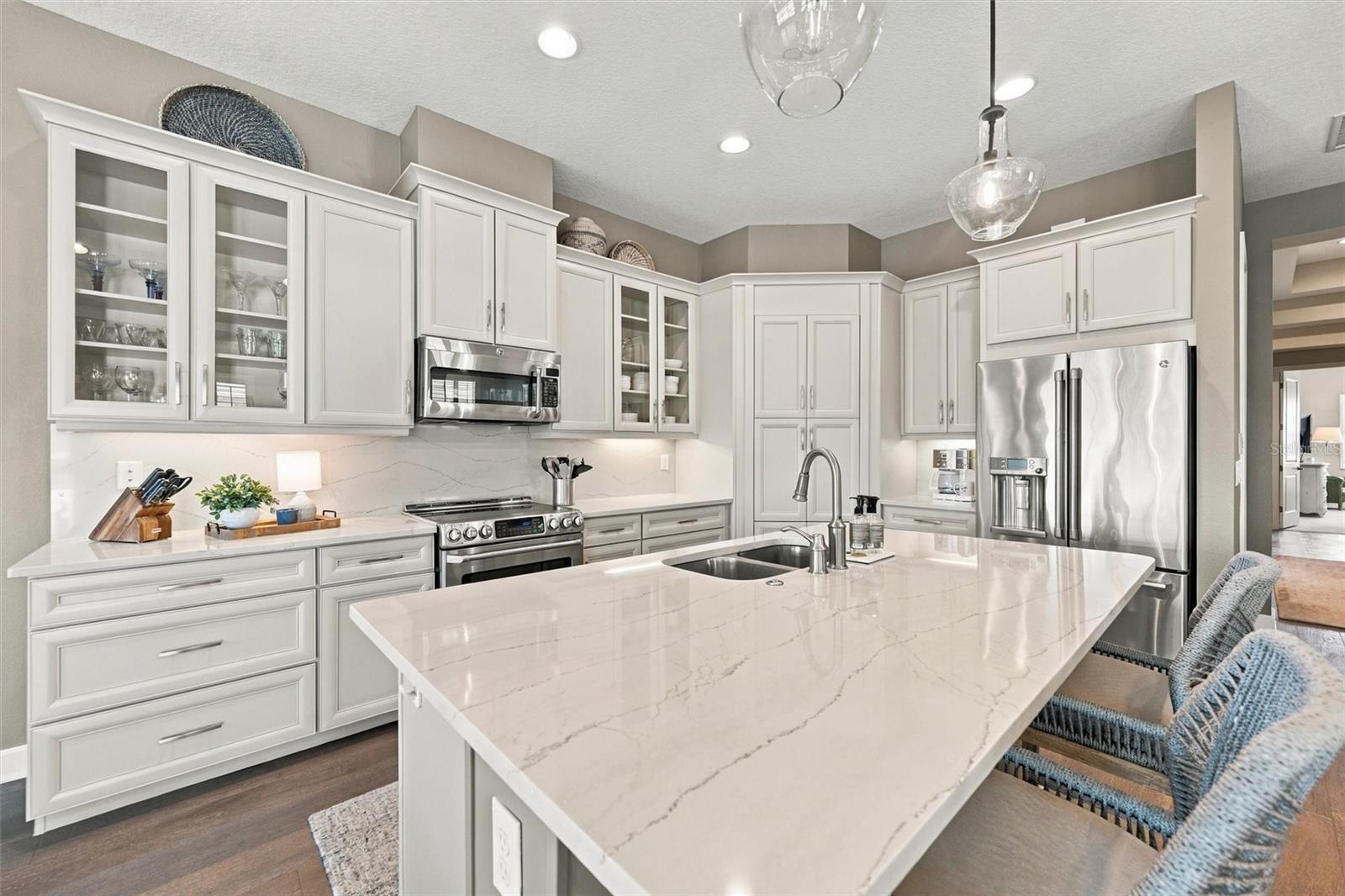 The well-designed kitchen shines with GE Caf stainless steel appliances, elegant quartz countertops, and a spacious walk-in pantry.