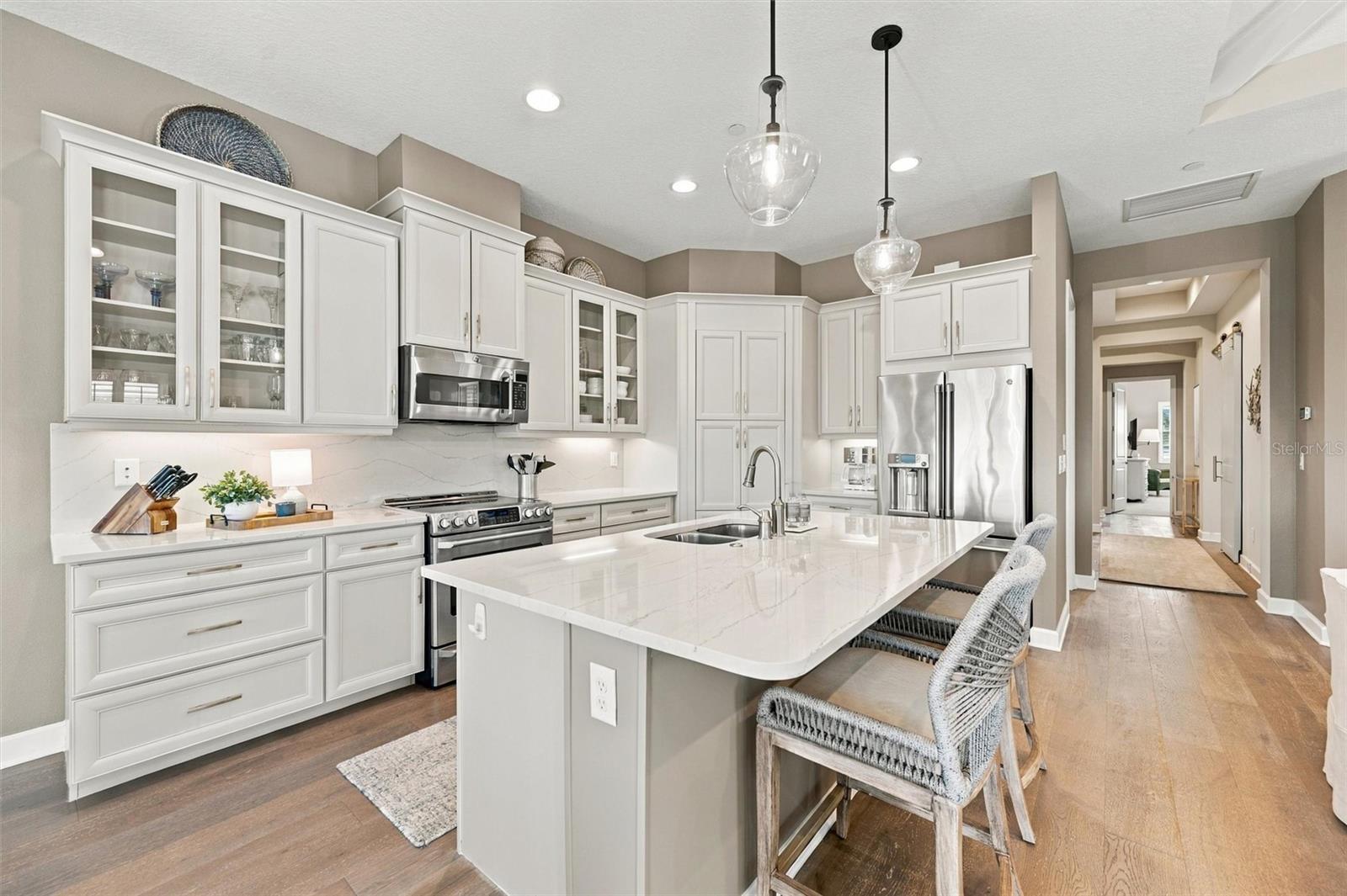 The well-designed kitchen shines with GE Caf stainless steel appliances, elegant quartz countertops, and a spacious walk-in pantry.