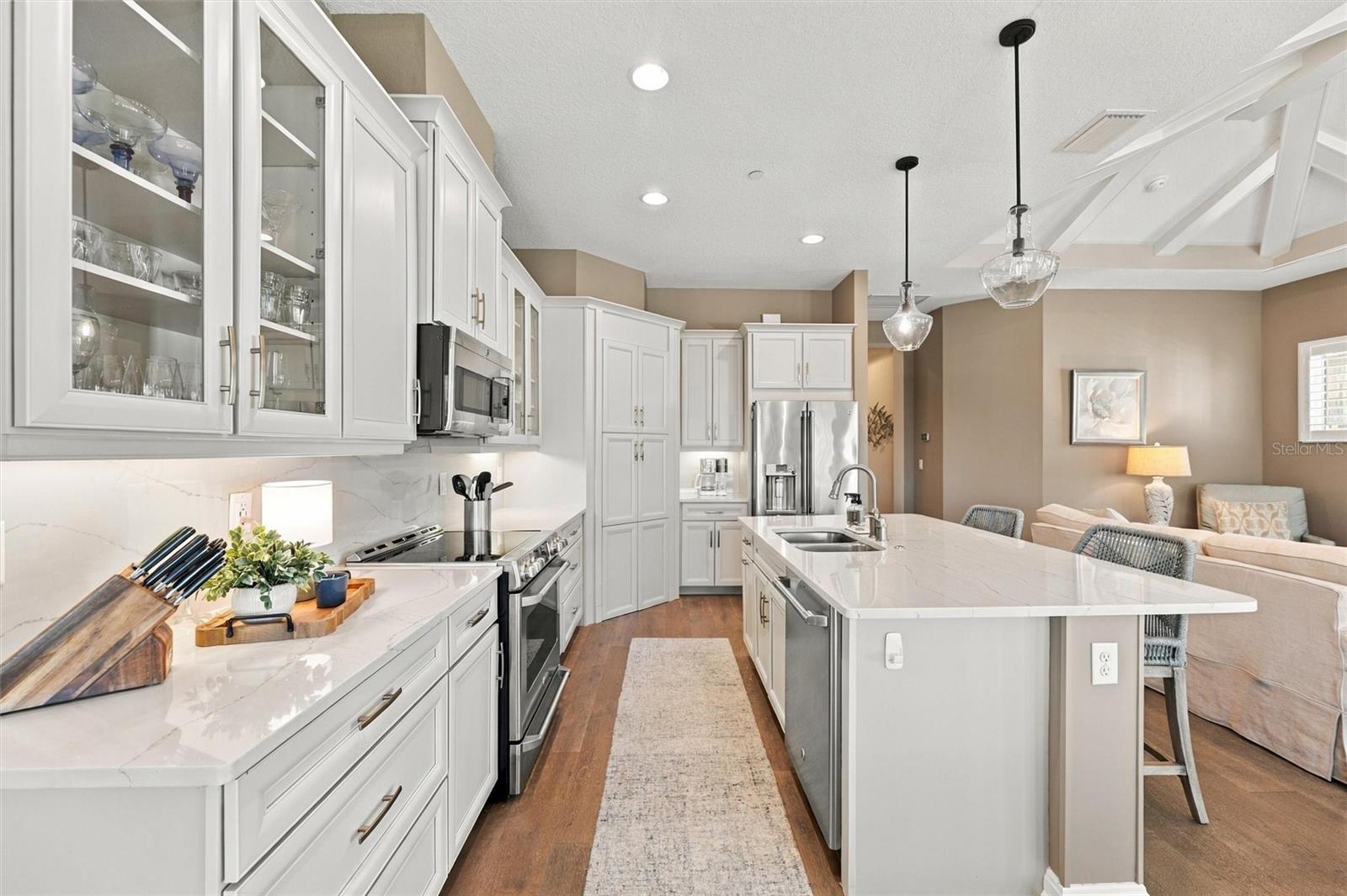 The well-designed kitchen shines with GE Caf stainless steel appliances, elegant quartz countertops, and a spacious walk-in pantry.