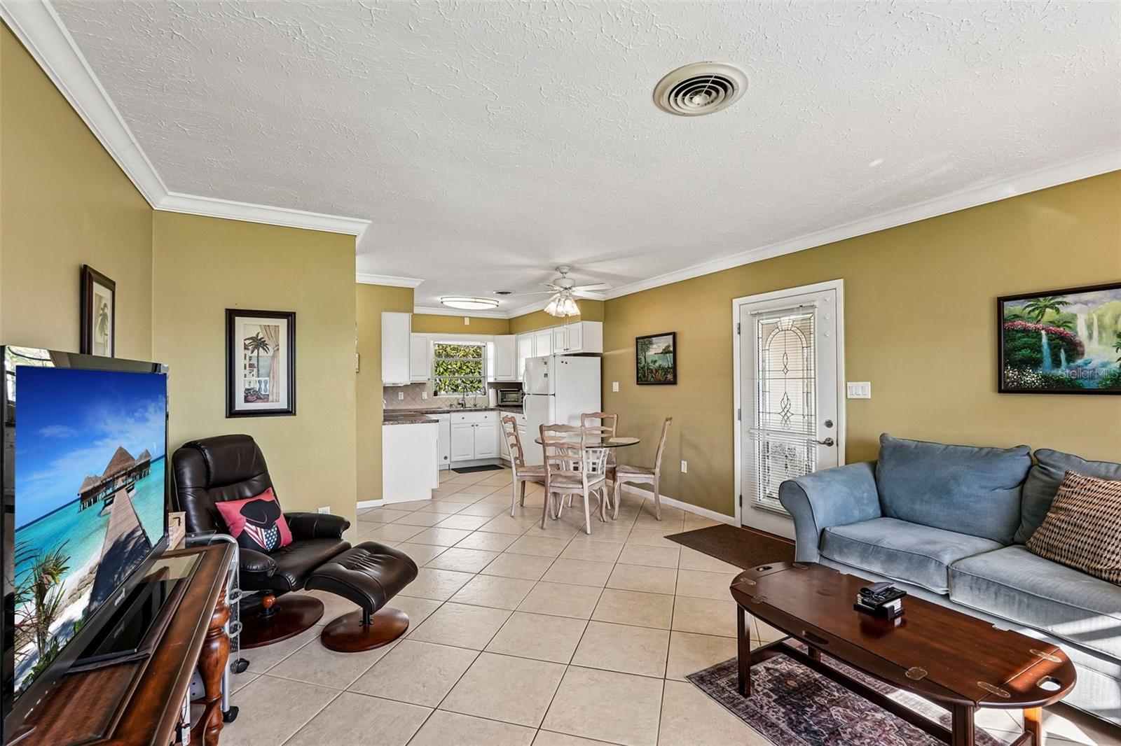309 - Open plan living room, casual dining adjoining kitchen. Door leads to carport.
