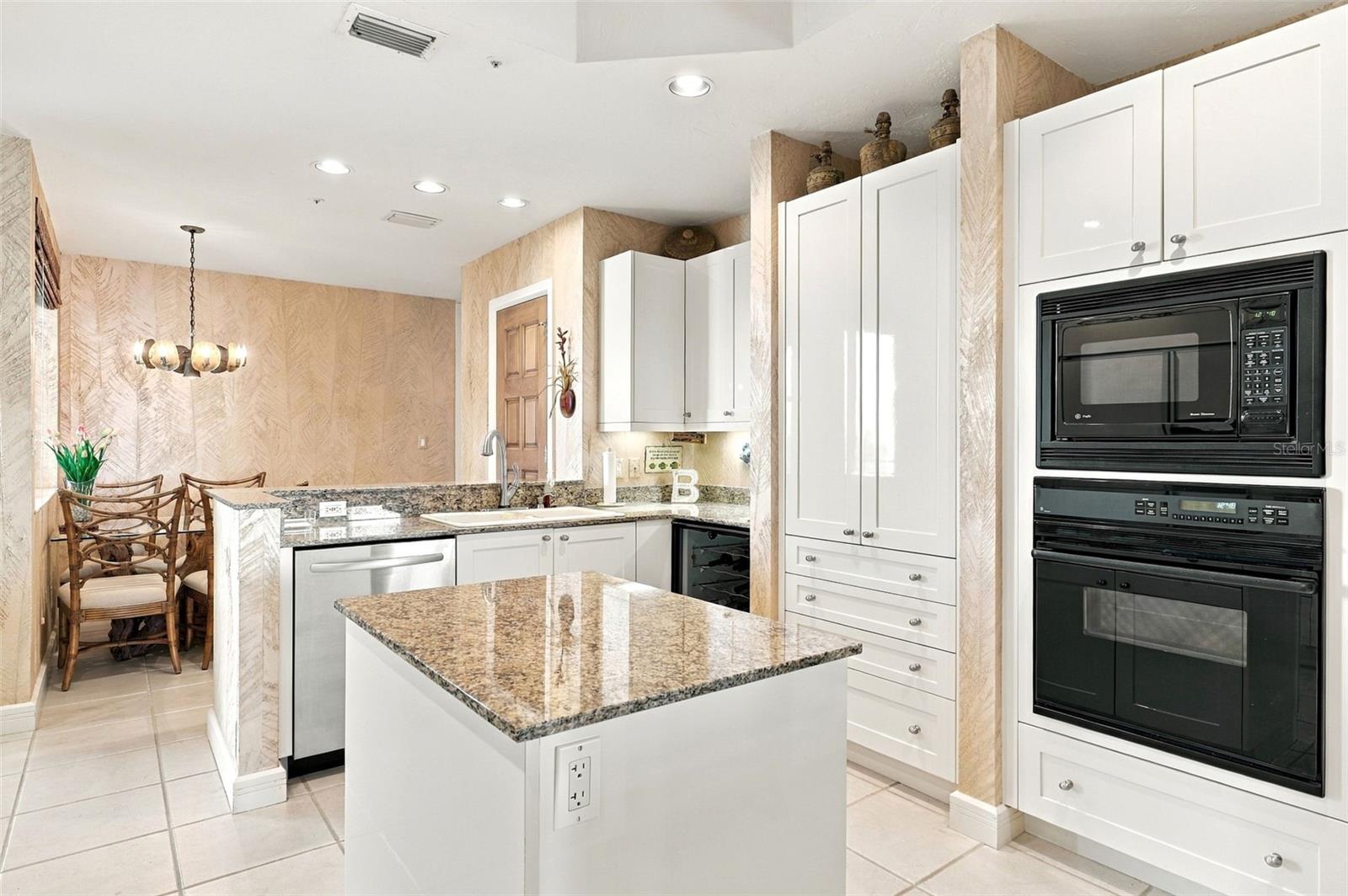 Thoughtfully designed kitchen with shaker style cabinetry, center island with cabinets and pull out drawers, planning desk, and wine refrigerator and closet pantry.