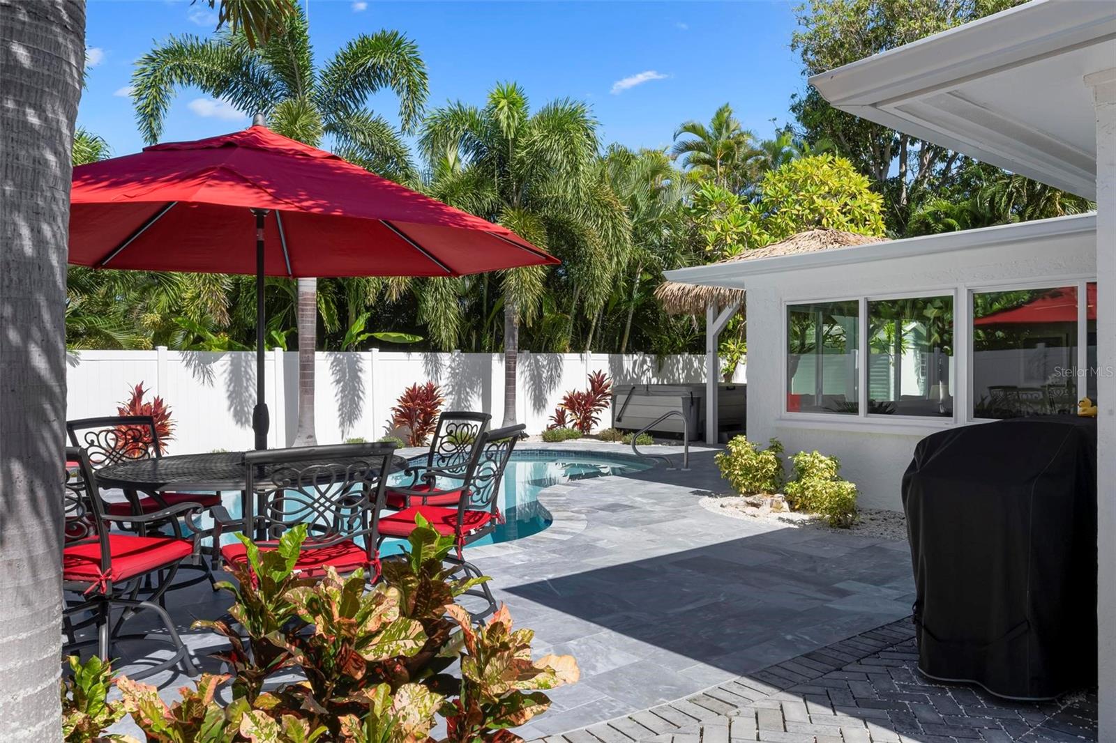 Pavered outdoor pool patio with heated saltwater pool and hot tub