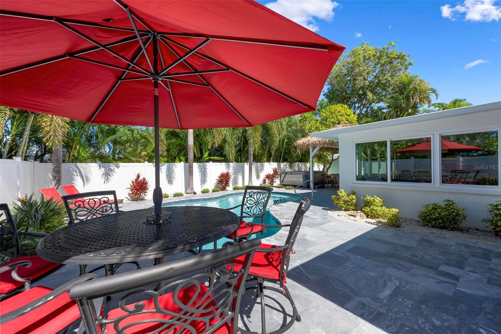 Pavered outdoor pool patio with heated saltwater pool and hot tub