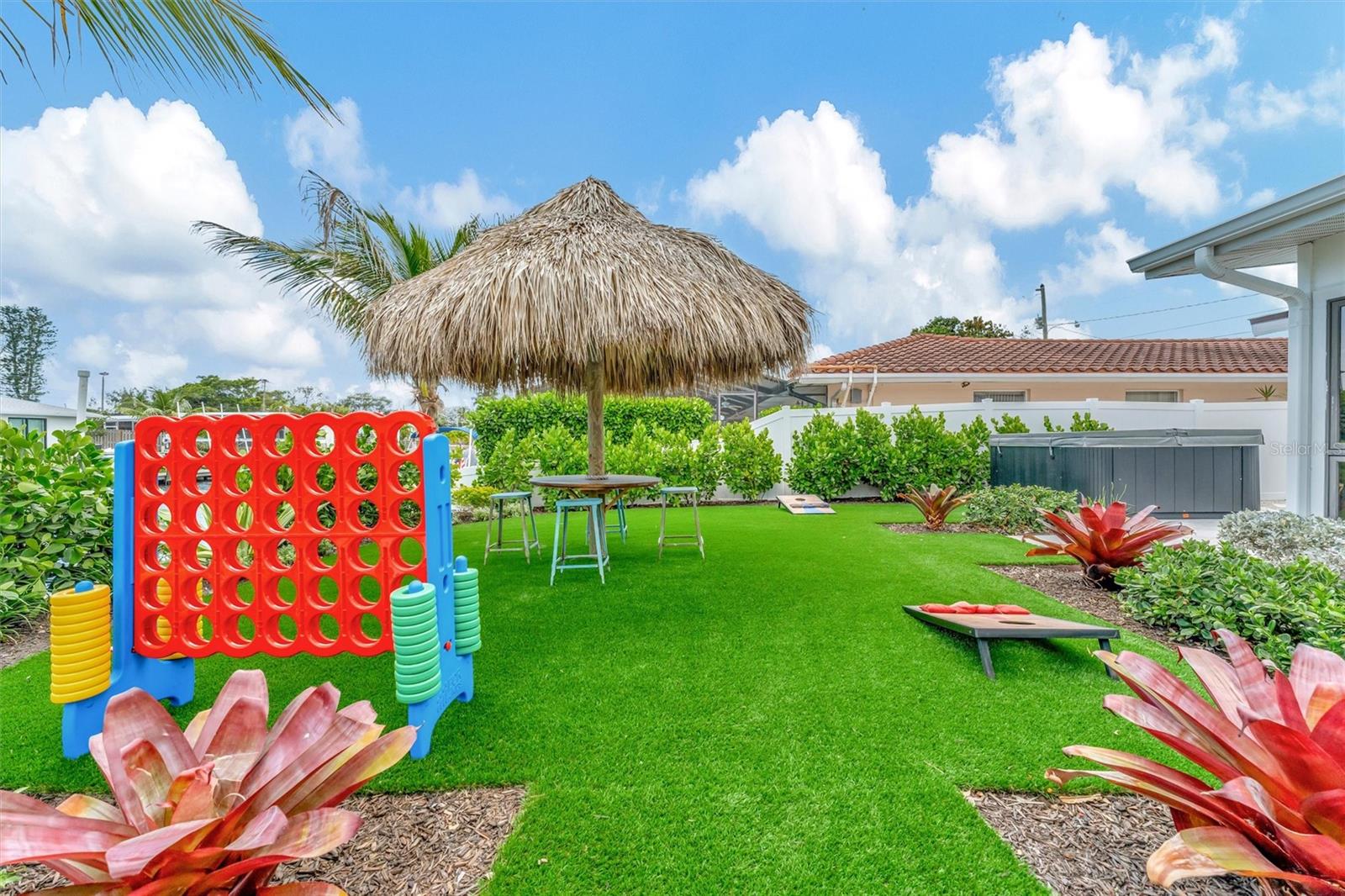 Covered lanai, multiple terraces, built-in propane grill, and tiki hut with turf games area.