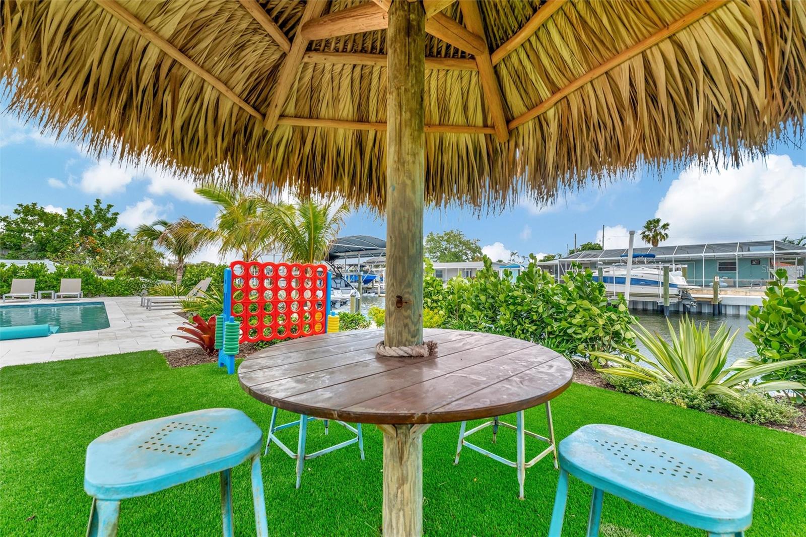 Covered lanai, multiple terraces, built-in propane grill, and tiki hut with turf games area.