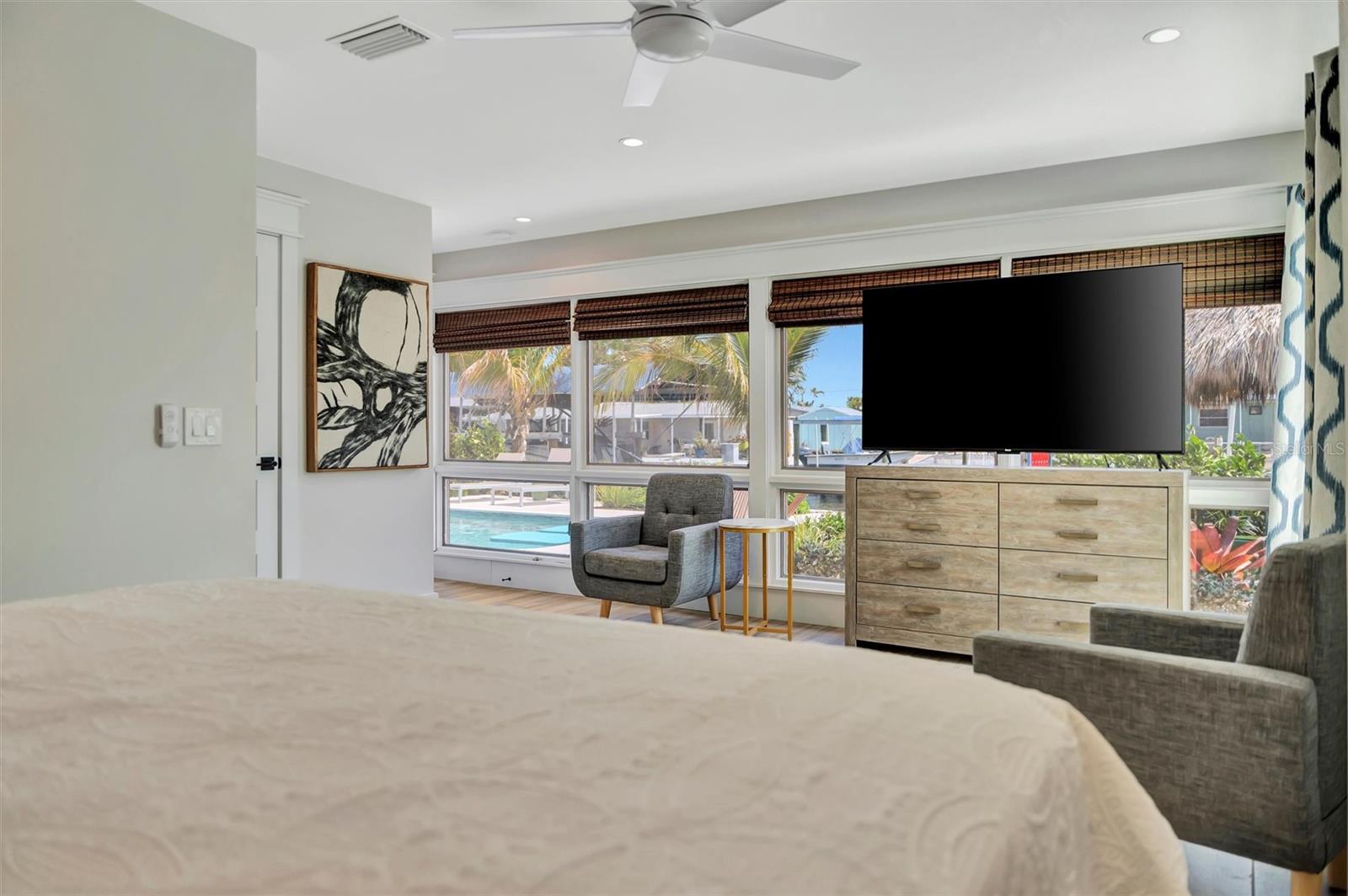 Primary suite with sliding glass doors, gorgeous views of the pool, turf area, and canal, plus an ensuite bathroom.