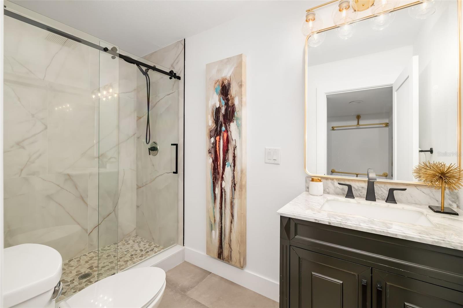 Full bath serving the additional bedroom and living area, featuring a glass-enclosed shower and updated finishes.