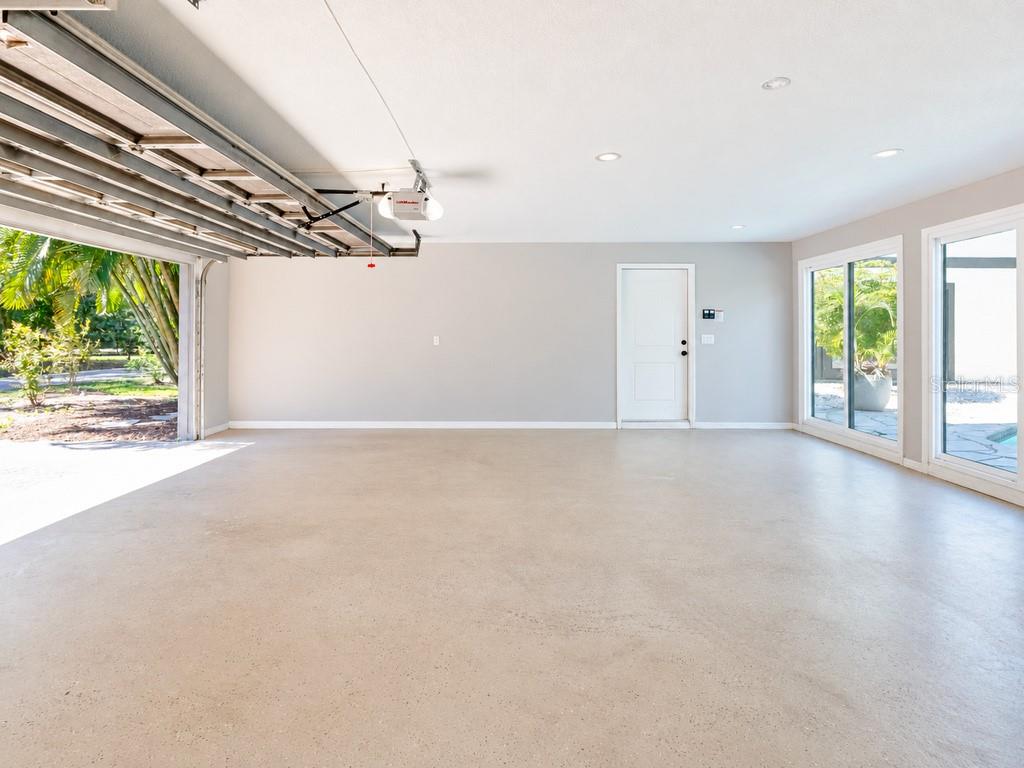 Expansive three-car garage offering exceptional space, with multiple glass doors providing natural light and convenient access toward the pool area
