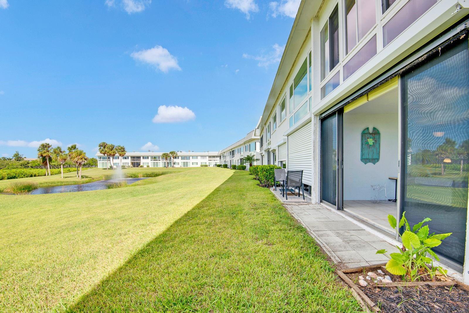 Outside back of condo lots of green grass and open area of water