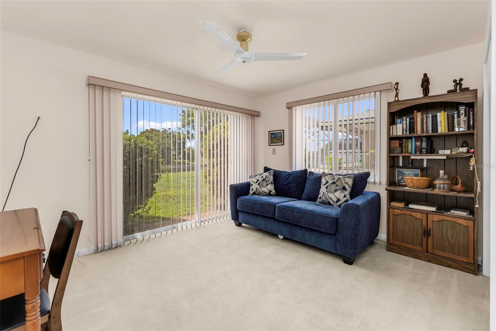Bedroom 3 (or Den/Office) with Sliders to outside and large closet, windows, and ceiling fan.