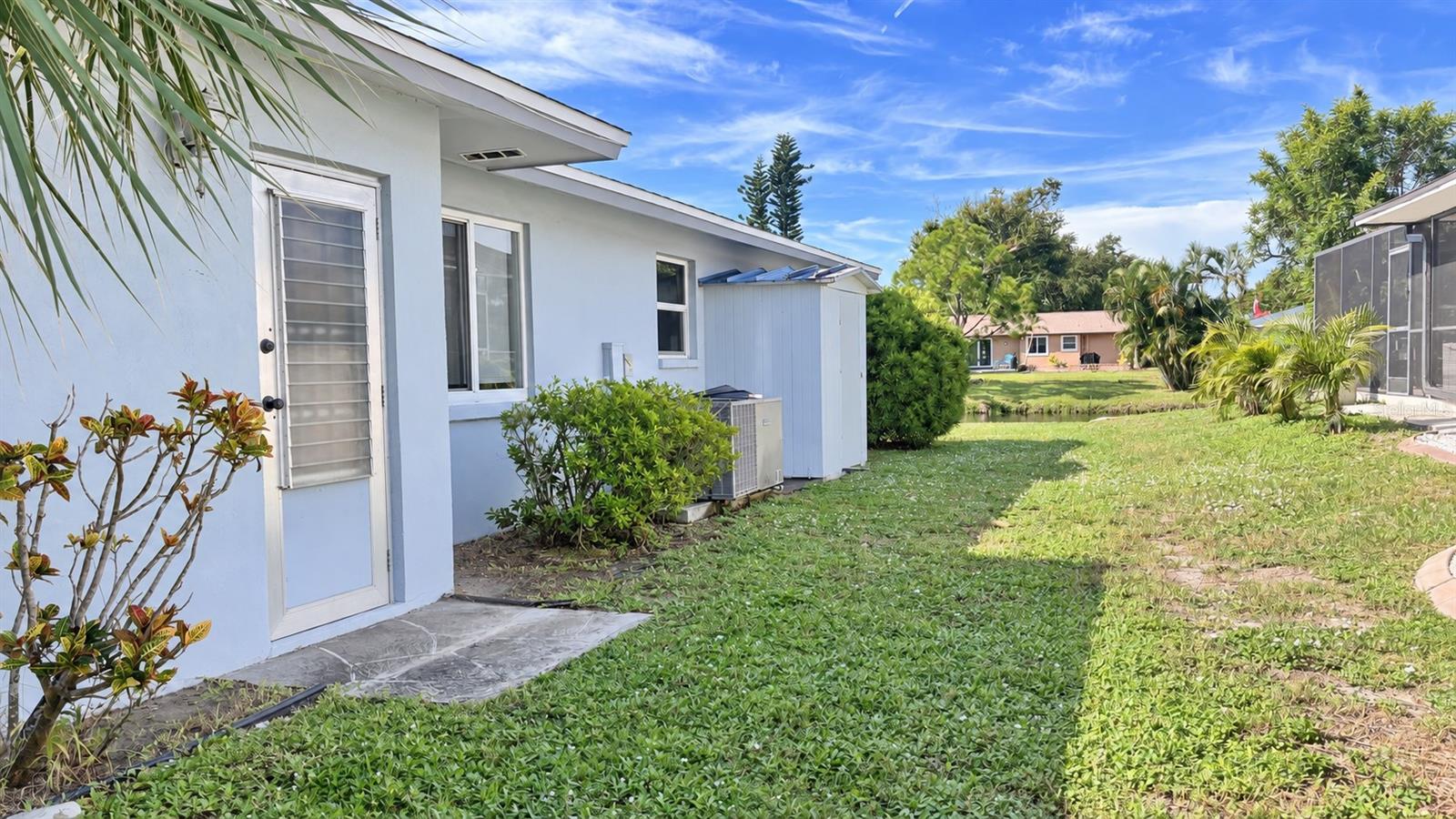 Side of home with doorway to garage, water side views, and storage shed.