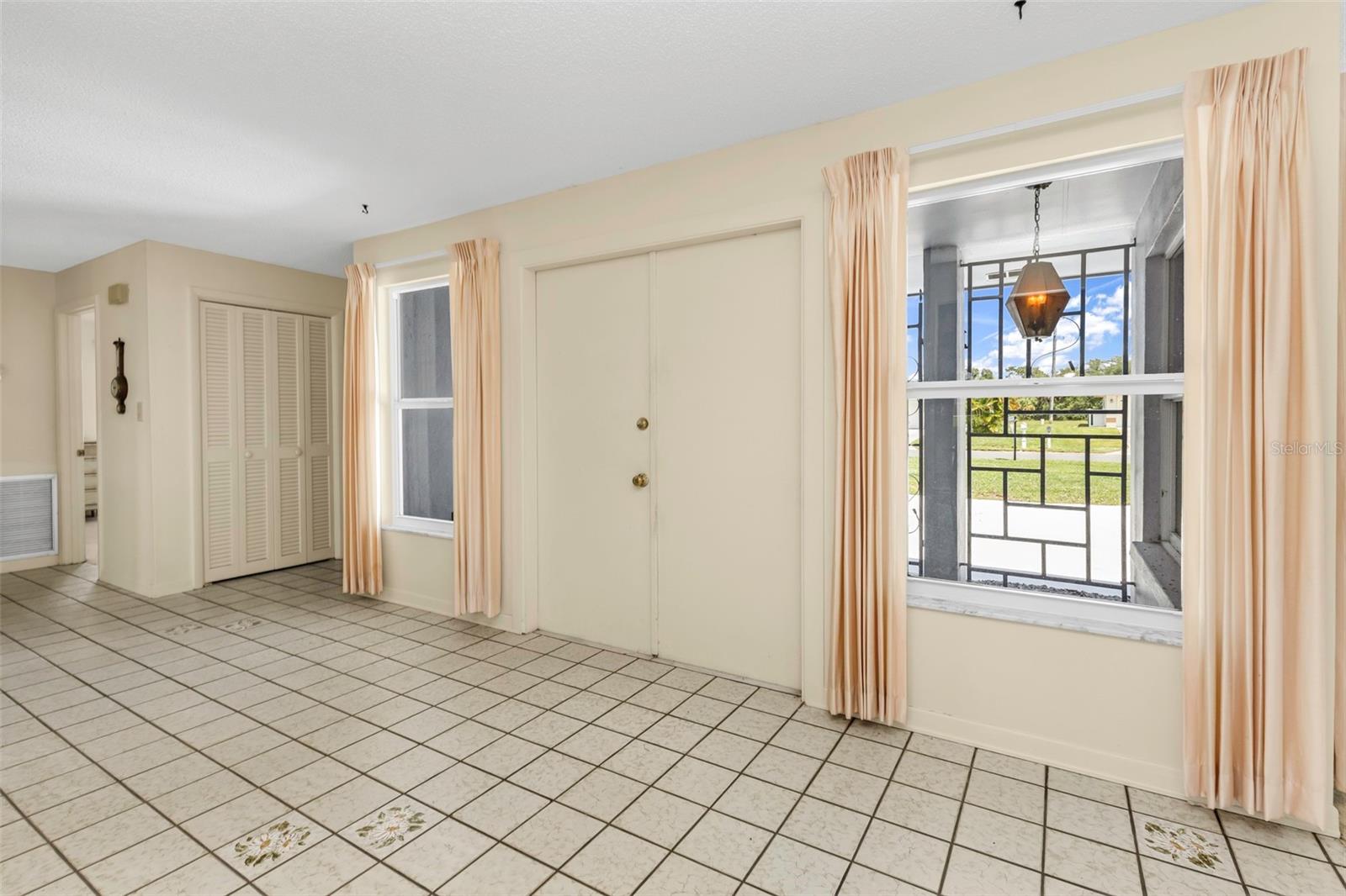 Entry way to the house through double doors, side entry to garage and laundry room, plus hallway closet/storage space and hallway bathroom.