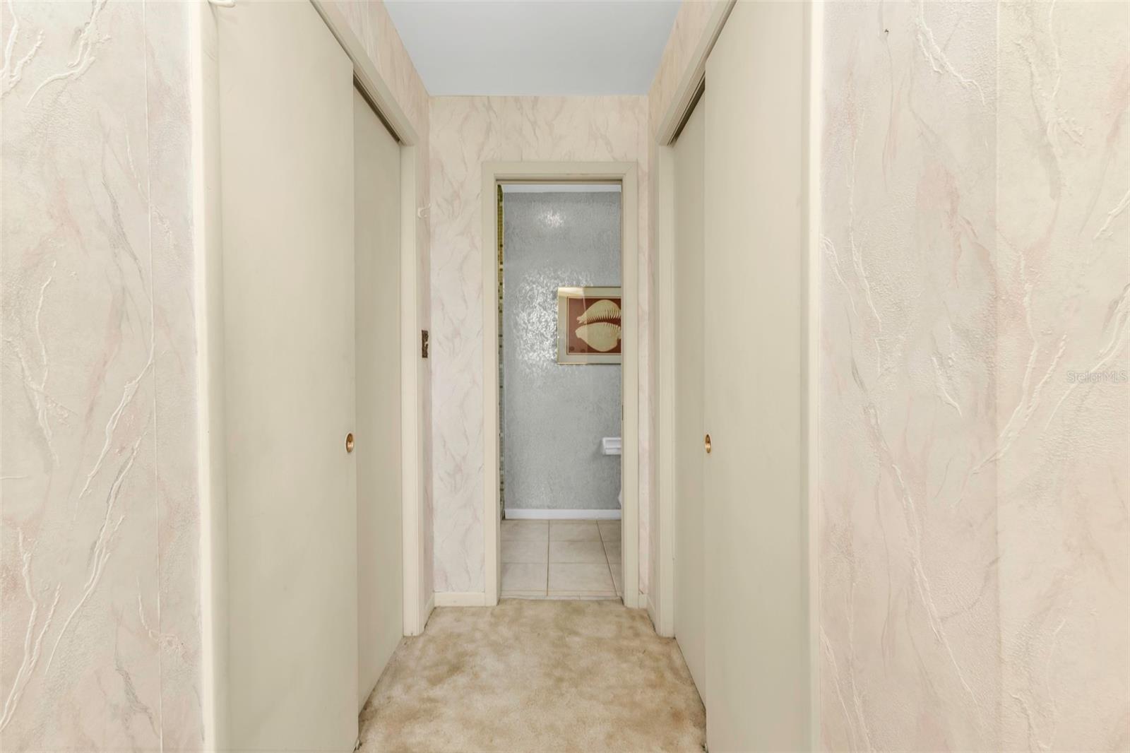 Closet on either side of private hallway located in primary bedroom