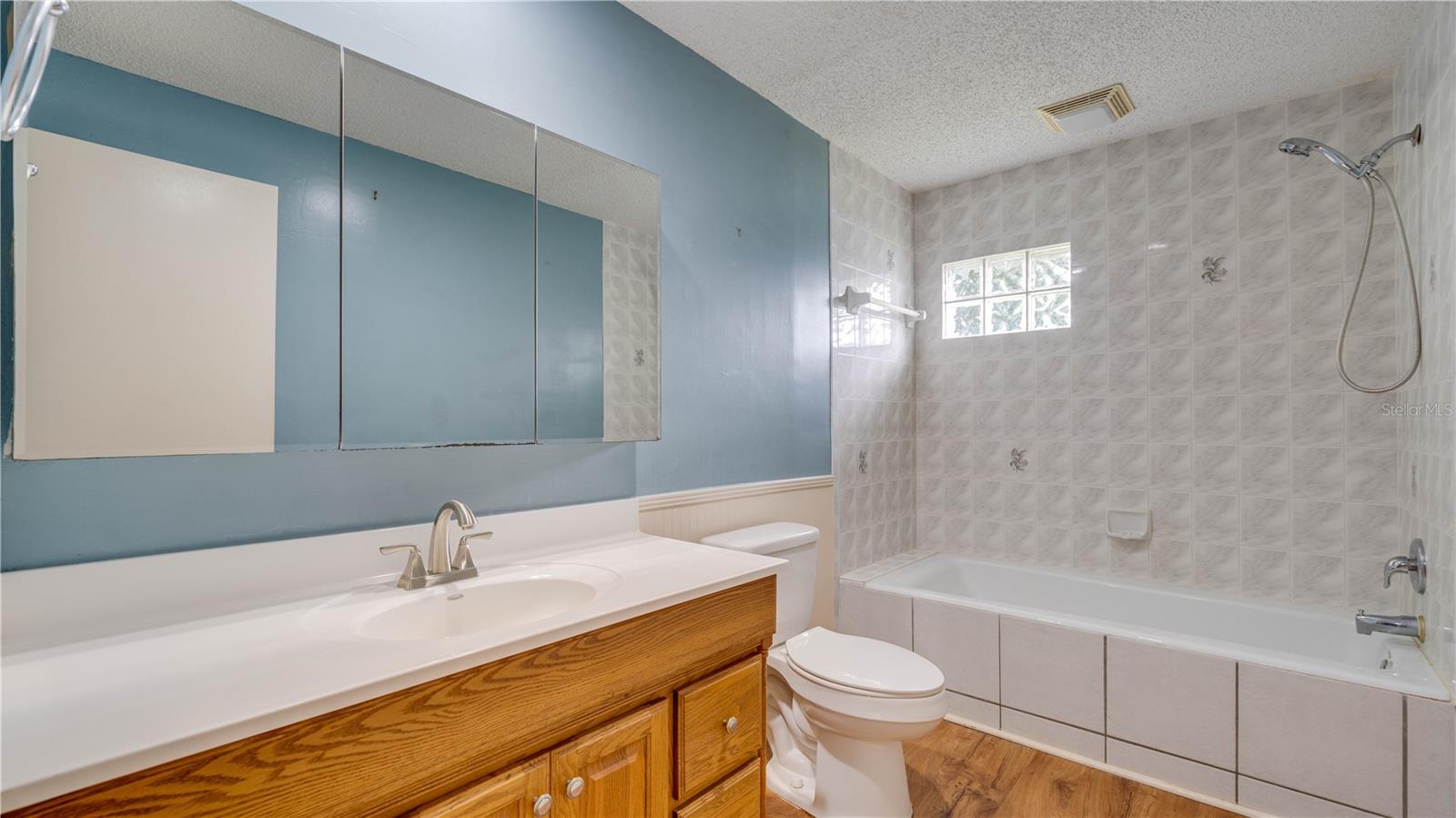 The 2nd bath features wood cabinetry, a large built-in medicine cabinet, and a tiled shower surround.