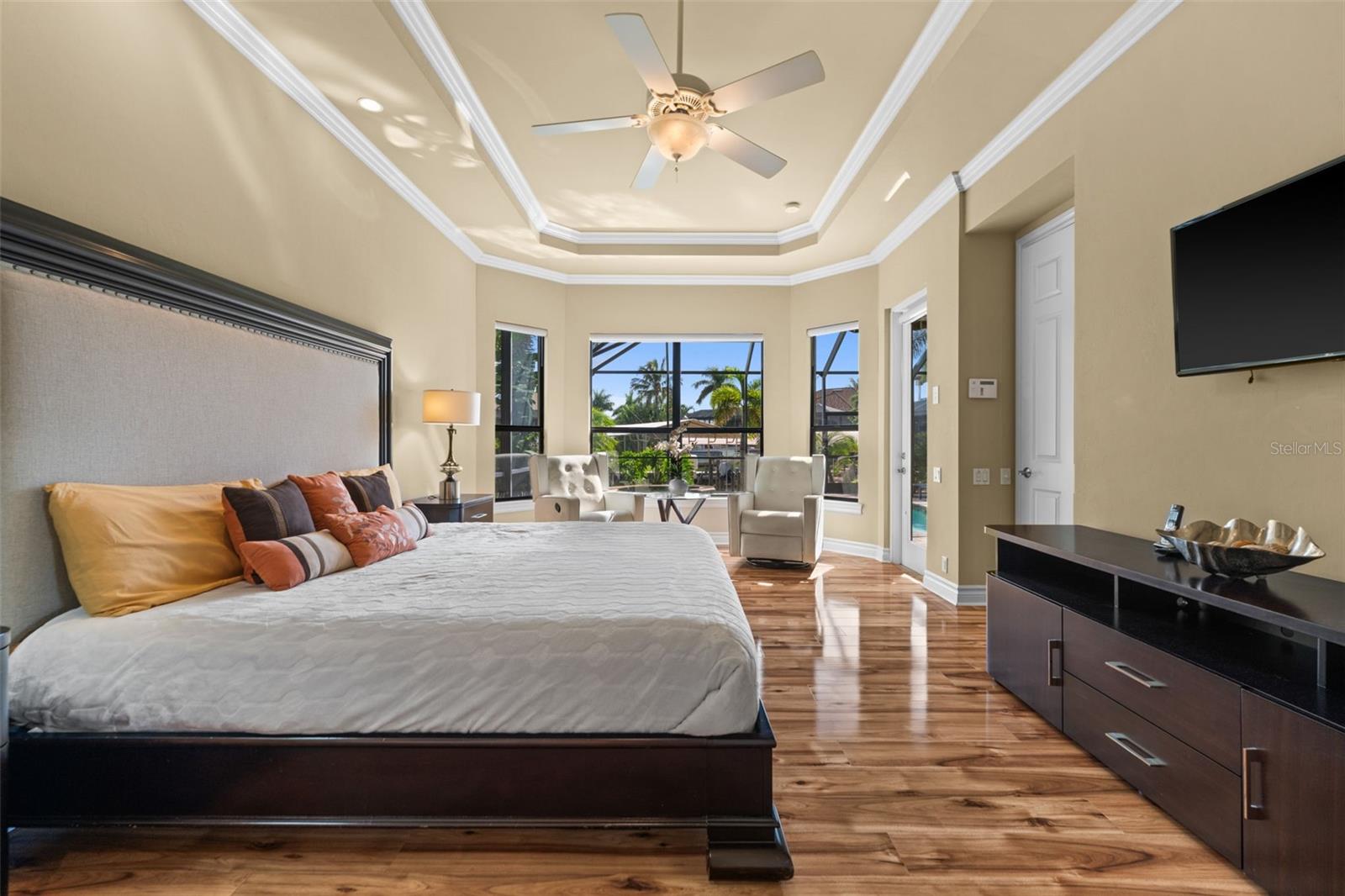 Primary bedroom with amazing wood floors and tray ceiling with crown molding