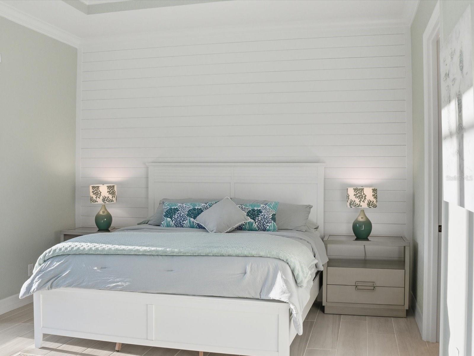 Shiplap accented wall along with crown molding around room and tray ceiling