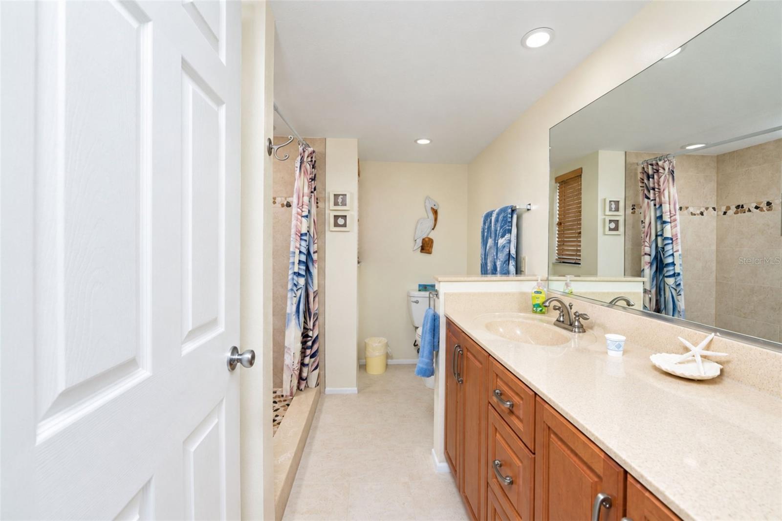 The primary bathroom has a solid surface countertop vanity with plenty of storage and tiled flooring.