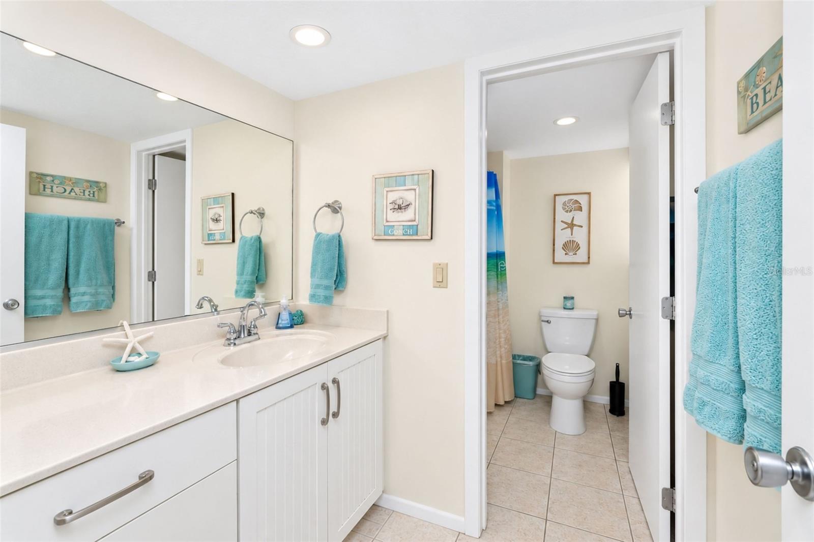 The guest bathroom features tiled flooring and an updated solid surface countertop vanity.