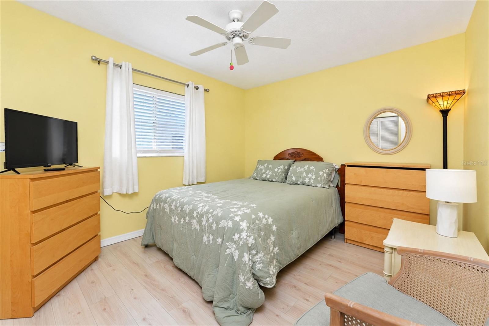 The guest bedroom features wood laminate flooring and a ceiling fan.