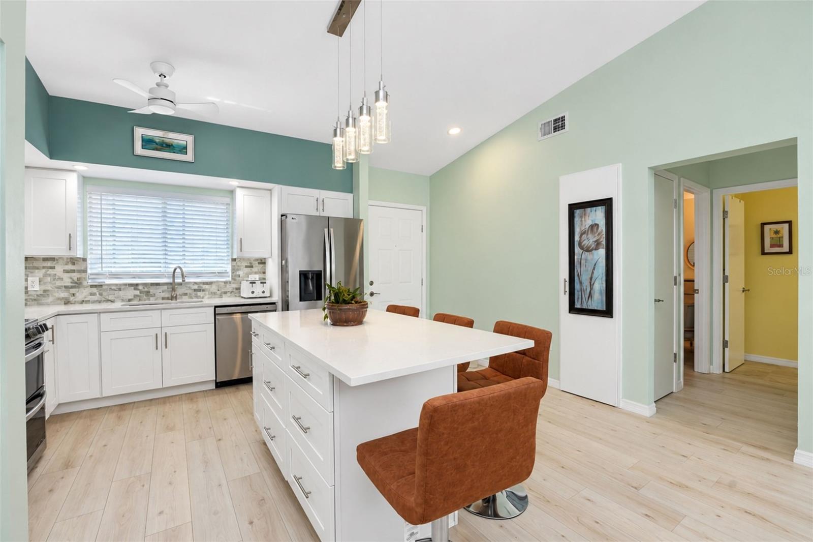 The kitchen features white cottage-style cabinetry, a decorative backslash and QUARTZ countertops.
