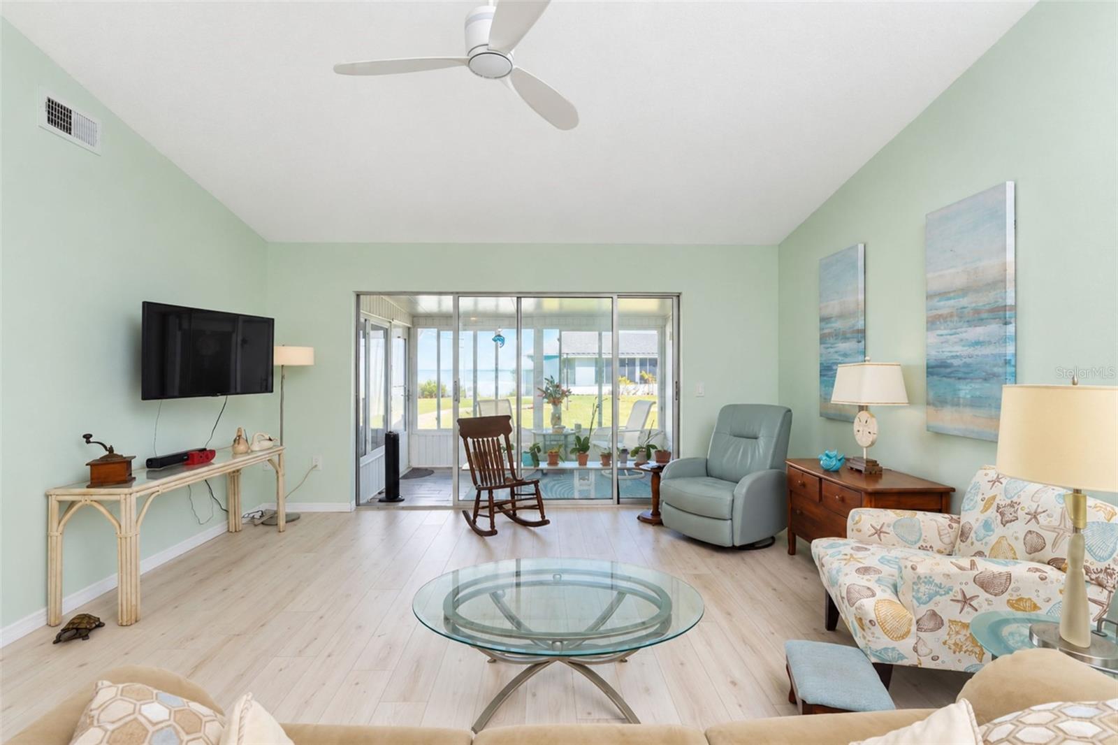 The living room has stylish wood laminate flooring, a ceiling fan and sliding glass doors to the Glass-Enclosed Florida room. The living room has stylish wood laminate flooring, a ceiling fan and sliding glass doors to the Glass-Enclosed Florida room.