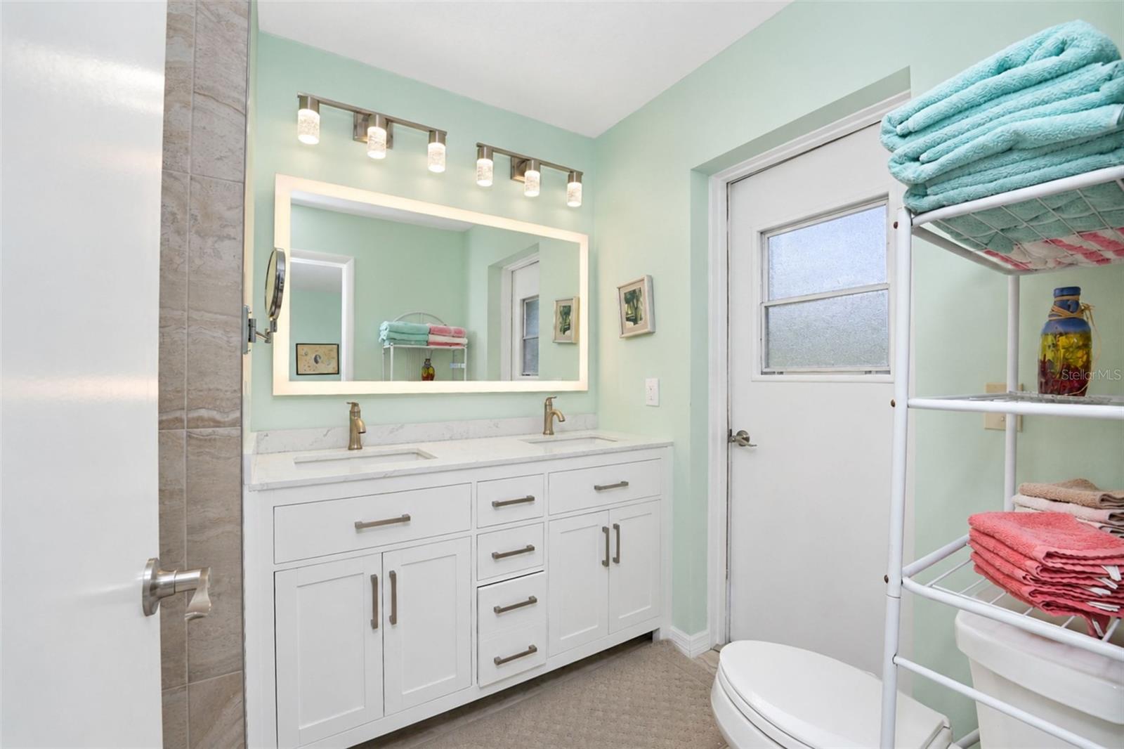 The updated ensuite bathroom features a new double sink vanity with solid-surface countertop, new faucets, touch control mirror, tiled flooring and direct access to the garage!