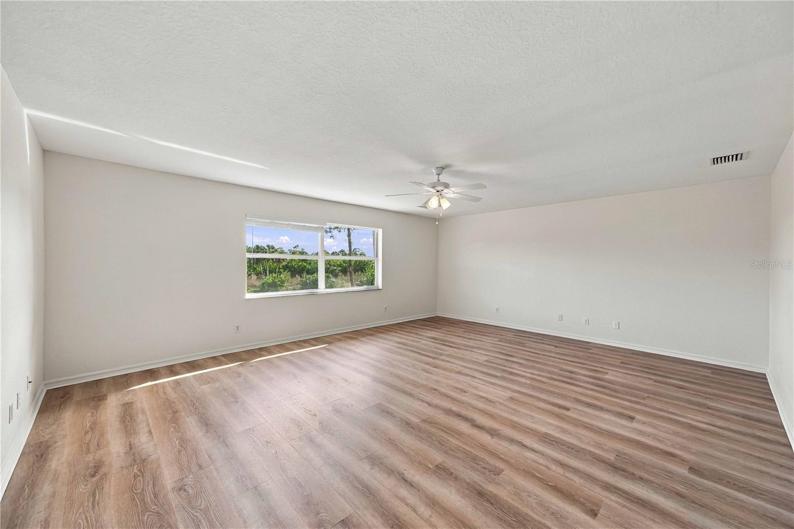 Great room with ceiling fan and vinyl plank flooring, enough room for pool table, bar, big screen tv and lounge chairs.
