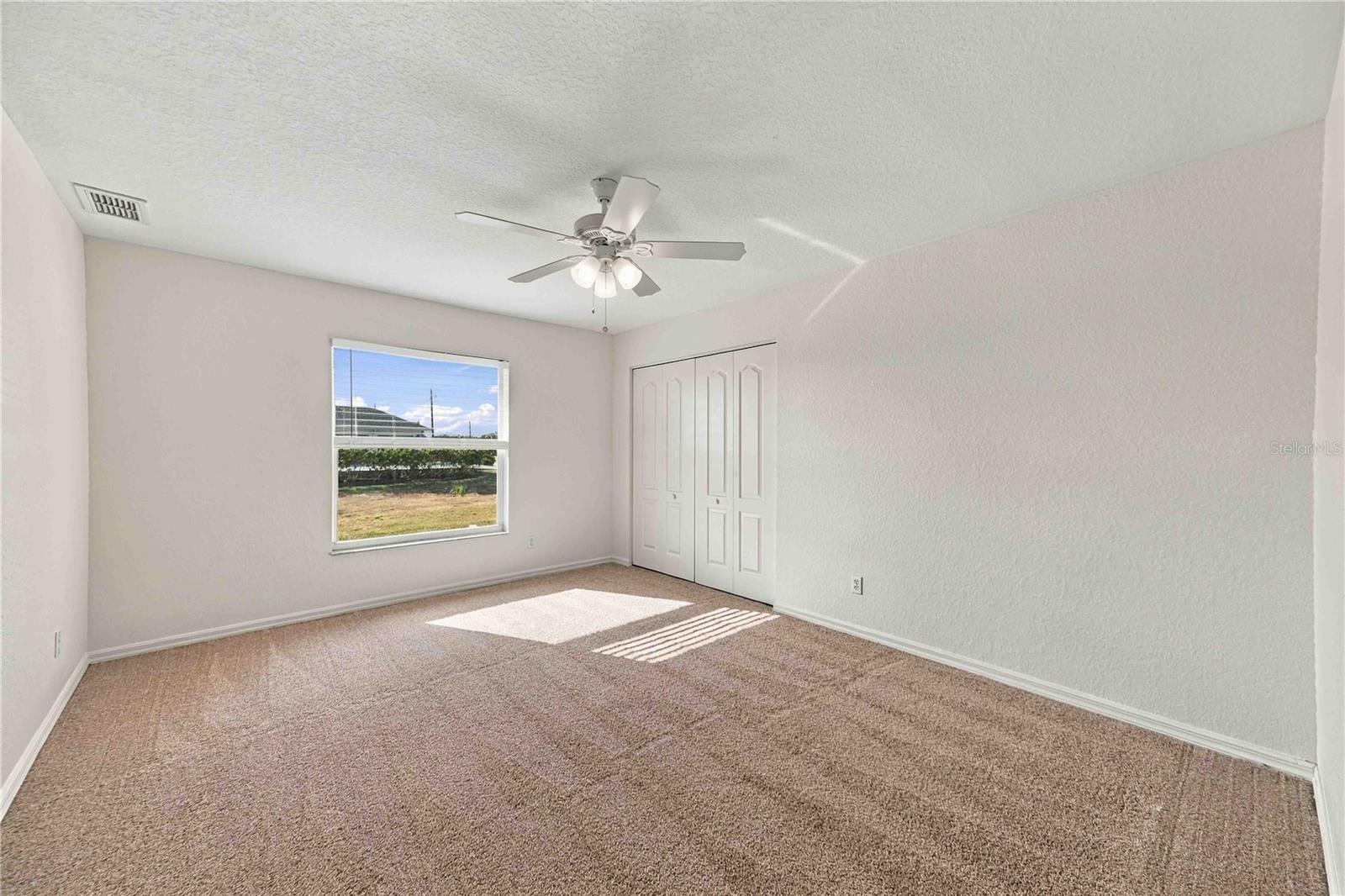 2nd bedroom with ceiling fan and large window