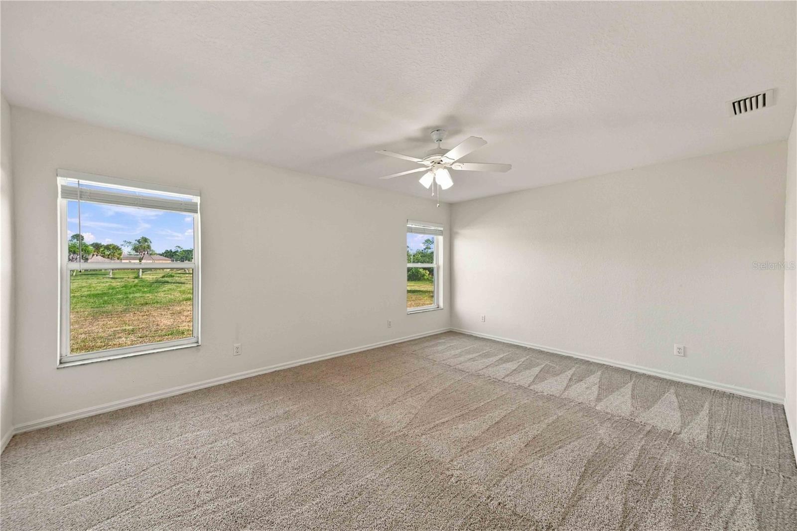 Primary bedroom with ceiling fan and carpet