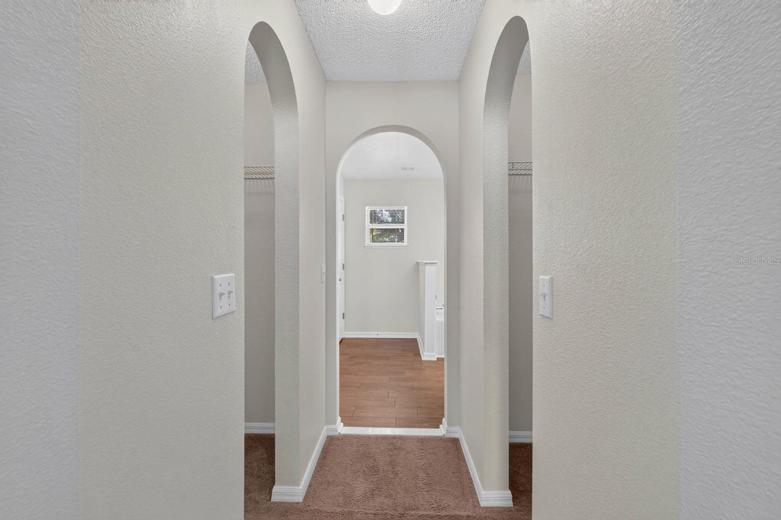 primary bedroom looking towards ensuite bath with his and her closets on either side before the bathroom
