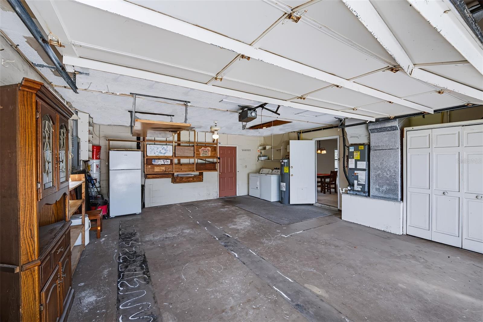 This 2-car garage exhibits plenty of storage space. This area also houses the HVAC, hot water heater and washer/dryer hook-up. Door to the right is an entry into the house, door at the back takes you out to the pool/lanai area
