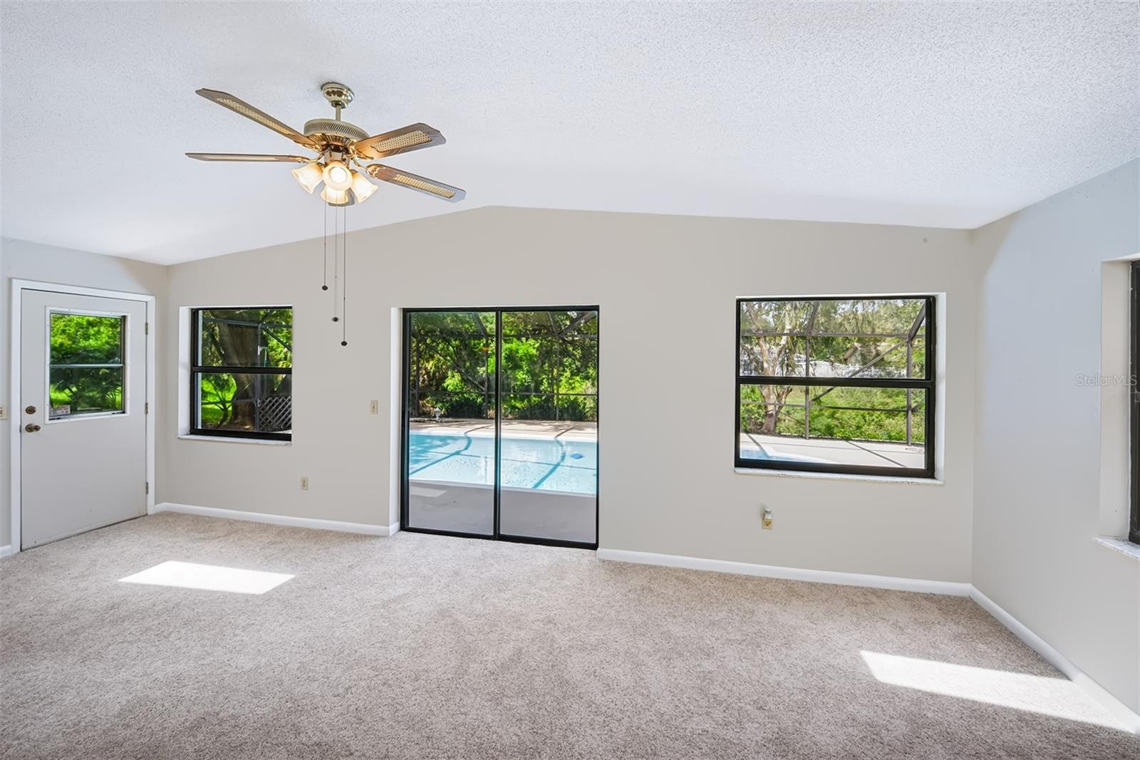 Florida room with side door and sliding glass doors out to the enclosed lanai/pool area