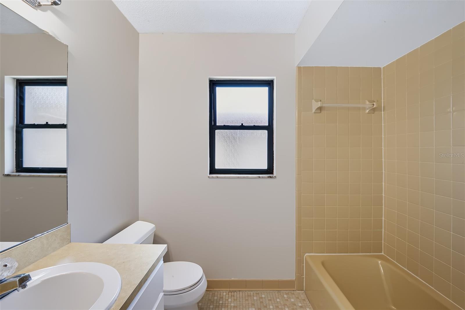 Secondary bathroom conveniently located in hall between both bedrooms. This bathroom also features retro-style glazed ceramic tile, it has a linen closet to the left of the sink with built-in medicine cabinet on wall, and has a tub/shower combination