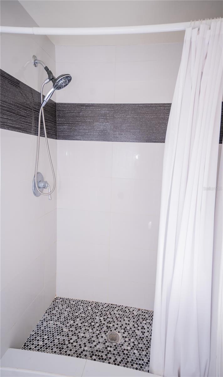 This custom shower features high-end designer tile work, premium fixtures, and luxury tile flooring.