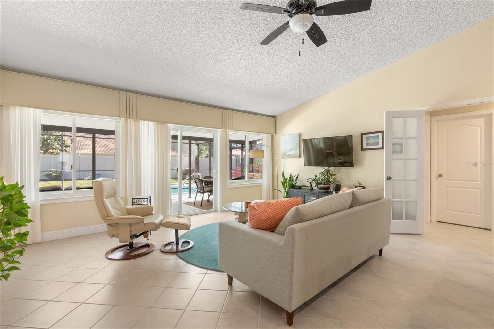 A cozy retreat for movie nights or quiet afternoons, this sunlit living room offers comfortable surroundings, generous windows, and sliding glass doors that lead directly to your poolside escape.