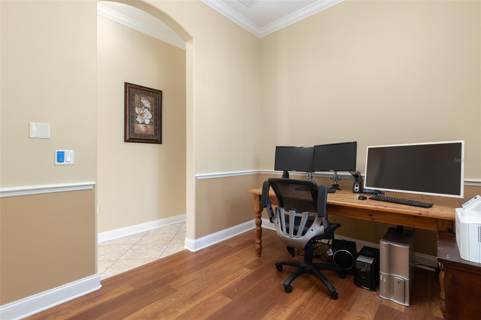 Another perspective of the office/den, highlighting the graceful arched entryway, crown molding, and chair rail detailing.