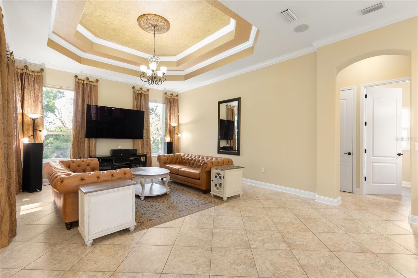 An elegant gathering room where a dramatic tray ceiling, crown molding and decorative lighting create a beautiful setting for relaxing and entertaining.