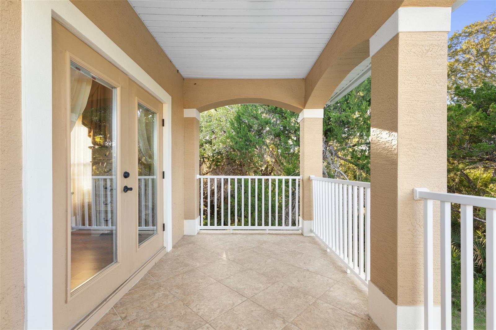 Another perspective of the covered balcony highlights its generous space, tiled flooring and direct access from the upstairs suite.