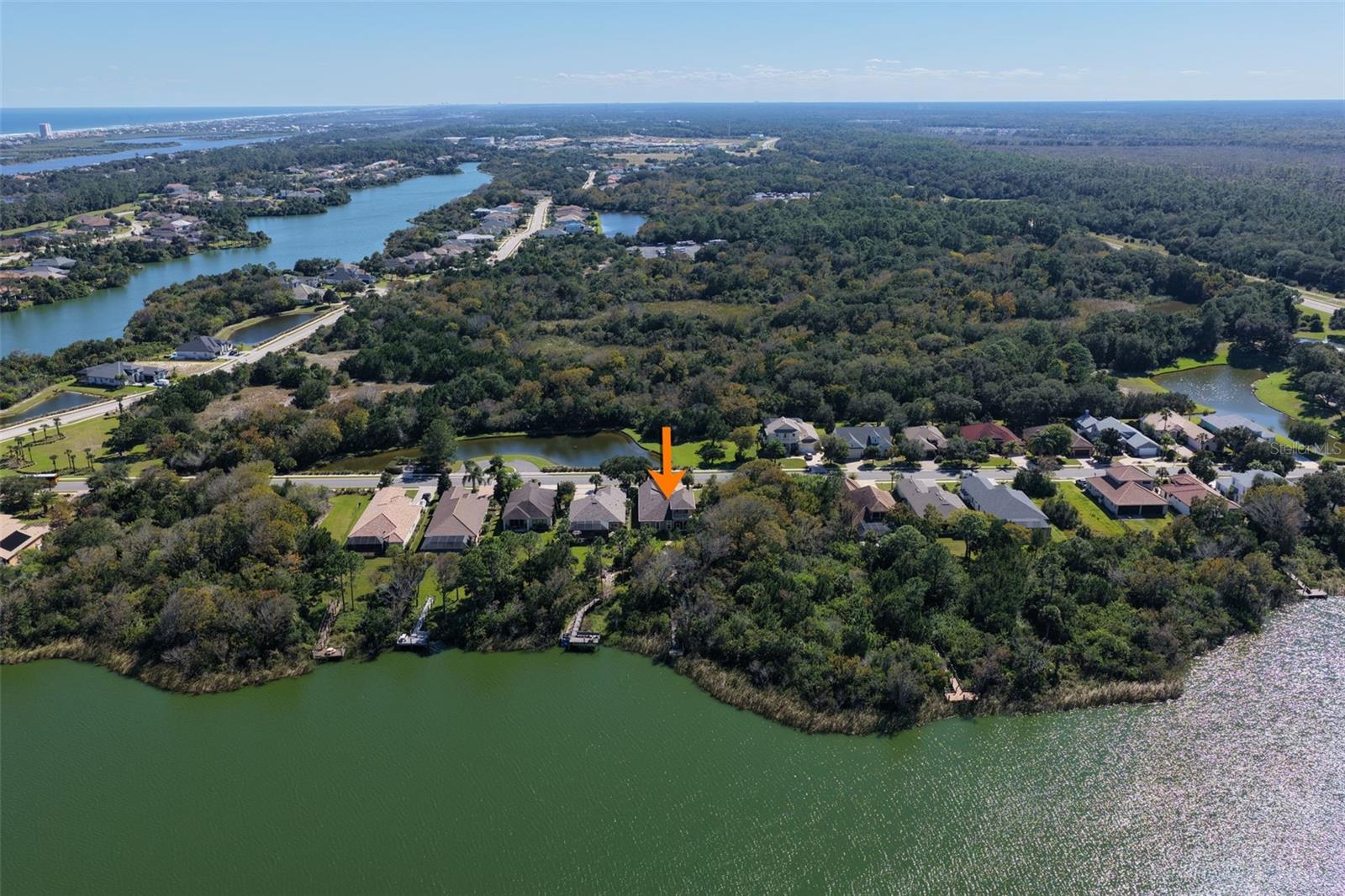 Aerial perspective showcasing the home's location along Emerald Lake, surrounded by natural greenery within Palm Coast Plantation.