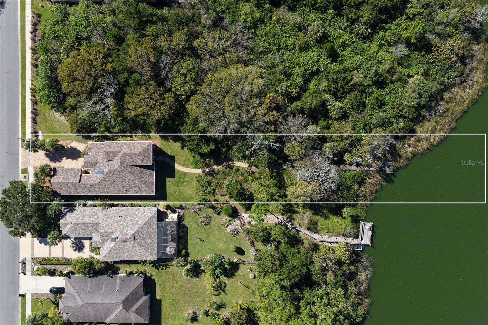 Overhead aerial showcasing the property's spacious 0.57-acre setting, natural conservation landscape, and private walkway leading to Emerald Lake.